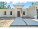 Close-up of a modern home entrance featuring a wood door, white columns and concrete walkway at 6877 Sw 131St Cir, Ocala, FL 34481