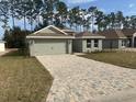 New house with a paved driveway and two-car garage, nestled amongst the trees at 7661 Sw 180Th Cir, Dunnellon, FL 34432