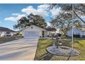 Charming single-story home with a well-manicured lawn, decorative garden, and inviting curb appeal under a sunny sky at 1904 Tweed Ct, Leesburg, FL 34788