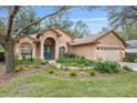 Tan house with teal door, arched entry, and lush landscaping at 19586 Sw 84Th Pl, Dunnellon, FL 34432