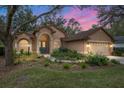 Attractive tan house with teal front door and well-manicured landscaping at 19586 Sw 84Th Pl, Dunnellon, FL 34432