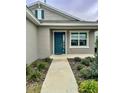 Inviting front entrance with teal door and walkway, enhancing the home's exterior at 7208 Sw 61St Sw Pl, Ocala, FL 34474