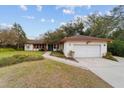 White single-story house with brown roof, two-car garage, and walkway at 9185 Sw 197Th Cir, Dunnellon, FL 34432