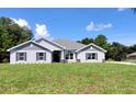 Finished new construction home featuring gray stucco, stone accents, shutters, and a landscaped yard at 12295 Sw 90Th Pl, Dunnellon, FL 34432
