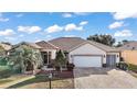 Single-story house featuring a white two-car garage and palm trees at 13077 Se 86 Ct, Summerfield, FL 34491