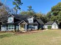Charming home with black roof, siding, manicured lawn and a detached garage for extra storage at 6701 Se 99Th Pl, Belleview, FL 34420