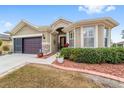 Tan house with brown doors, landscaping, and a two-car garage at 7358 Sw 101St Ave, Ocala, FL 34481