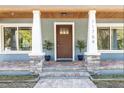 Charming home entrance with a wood door, stone accents, and decorative columns at 11759 Bostick St, Dunnellon, FL 34432