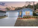 Newly built home with light blue exterior, white garage door, and stone accents at 13824 Se 42 Ave, Summerfield, FL 34491