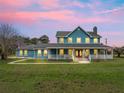 Two-story home exterior with wrap-around porch at dusk at 20921 Sw 36Th St, Dunnellon, FL 34431