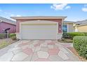 Two-car garage with a patterned stone driveway at 6751 Sw 91St Cir, Ocala, FL 34481