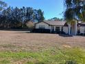 House with a large grassy yard and mature trees in the background at 19950 Ibis Ct, Dunnellon, FL 34432