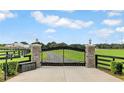 Ornate black metal entrance gate with stone pillars leading to a charming home and lush green landscape at 12000 S Highway 475, Ocala, FL 34480