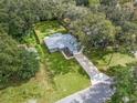An aerial view shows the well-maintained property with a long driveway and mature trees providing shade at 205 Brevard Ave, Lady Lake, FL 32159