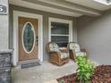 Charming front porch featuring a decorative front door, two wicker chairs and a small garden at 205 Brevard Ave, Lady Lake, FL 32159