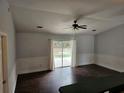 Open-concept living room featuring sliding glass doors, dark laminate flooring, and updated fixtures at 3752 Se 130Th St, Belleview, FL 34420