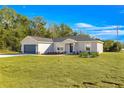 Newly built home features a gray exterior, dark gray garage door, and lush green lawn at 4424 Se 137Th Pl, Summerfield, FL 34491