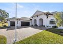 White house with three-car garage and a brick driveway at 5141 Greens Dr, Lady Lake, FL 32159