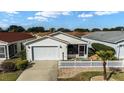 Aerial view of a well-maintained home with an attached garage and a white picket fence at 1112 Carvello Dr, The Villages, FL 32162