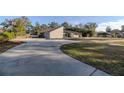 Tan house with a large, curved driveway and grassy yard at 3261 Se 41St Pl, Ocala, FL 34480