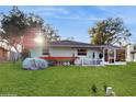 View of a large, grassy backyard with a screen enclosed porch attached to the house at 35428 Crescent Dr, Fruitland Park, FL 34731