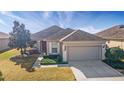 Inviting single-story home showcasing a manicured lawn, tidy landscaping, and a spacious two-car garage at 9858 Sw 75Th Street Rd, Ocala, FL 34481