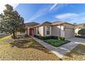 Charming single-story home featuring a well-maintained lawn, landscaped bushes, and a red front door at 9858 Sw 75Th Street Rd, Ocala, FL 34481