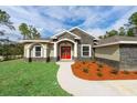 Eye-level capture of the home's striking red double-door entrance framed by stately white columns and stone accents at 12217 Sw 67Th Ln, Ocala, FL 34481