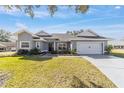 Gray house with white accents, two-car garage, and landscaped yard at 17470 Se 115Th Terrace Rd, Summerfield, FL 34491