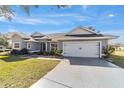 Gray house with white accents, two-car garage, and landscaped yard at 17470 Se 115Th Terrace Rd, Summerfield, FL 34491