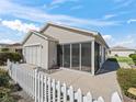 House exterior showcasing a screened-in porch and a white picket fence at 1817 Hallandale Ln, The Villages, FL 32162