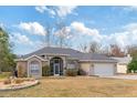 Tan single story house with gray roof, screened porch, and landscaped yard at 7727 Sw 102Nd Loop, Ocala, FL 34476