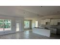 Open-concept living space with modern tile floors, large windows and an unfinished kitchen area at 13 Nw 45Th Loop, Ocala, FL 34475