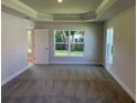 Spacious primary bedroom with tray ceiling and large windows providing natural light at 13 Nw 45Th Loop, Ocala, FL 34475