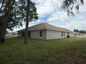 A lawn and the rear view of a single story home with double hung windows, a brown roof, and tan colored stucco at 7 Nw 45Th Loop, Ocala, FL 34470