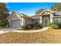 Front view of a single-story house with a teal front door and landscaping at 8120 Sw 56Th Ter, Ocala, FL 34476