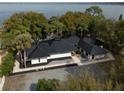 Beautiful exterior shot showcasing the modern design of the home with black roof, surrounding trees and water view at 13061 Se 158Th Ln, Weirsdale, FL 32195