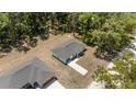 Aerial view of a single-Gathering home with grey roof, set among many trees, with a long driveway at 15304 Sw 27 Ln, Ocala, FL 34481