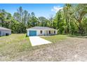 Inviting single-Gathering home showcasing a blue garage door, set amongst a backdrop of tall trees at 15304 Sw 27 Ln, Ocala, FL 34481