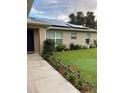 Charming home exterior featuring lush green lawn, garden beds, solar panels and a welcoming entrance at 1561 Ne 160Th Pl, Citra, FL 32113