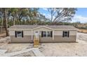 Tan mobile home with gray trim, wood steps, and a gravel driveway at 6555 Se 165Th Ave, Ocklawaha, FL 32179