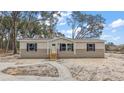 Tan mobile home with gray trim, wood steps, and a gravel pathway at 6555 Se 165Th Ave, Ocklawaha, FL 32179