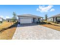 One-story home with light gray siding, paver driveway, and landscaped yard at 7865 Sw 89Th Cir, Ocala, FL 34481