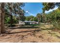 Expansive backyard featuring a covered patio, mature trees, and a fenced perimeter at 9352 Ne 27Th Ter, Anthony, FL 32617