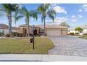 Inviting single-story home featuring lush lawn, mature landscaping, a paver driveway, and a two-car garage at 9651 Se 137Th Street Rd, Summerfield, FL 34491