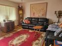 Living room features a red rug and black leather furniture at 11256 Sw 78Th Ave, Ocala, FL 34476