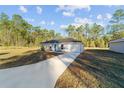 Newly built home with gray siding and teal front door, driveway and landscaping at 24025 Nw Foxglove Lane, Dunnellon, FL 34431