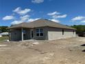 View of the rear of a one-story home, showcasing the covered patio, stucco exterior, and expansive backyard at 3212 Ne 46Th Ave, Ocala, FL 34470