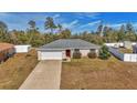 Angle front view of a single Gathering home, showcasing long driveway, attached garage and red front door at 13661 Sw 43Rd Cir, Ocala, FL 34473