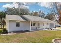 Charming single-story home with an attached garage, manicured lawn, and quaint covered porch with hanging plants at 1517 New Abbey Ave, Leesburg, FL 34788